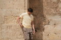 Man leaning against a rough stone wall in a Freedom Fit Tee in Butter Yellow